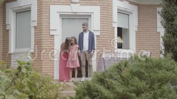 幸福的一家人一起站在门廊上母亲和父亲吻别了小女儿她离开了家视频的预览图