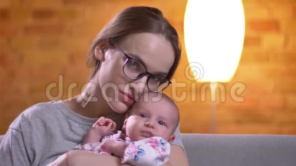 母亲抱着哭泣的新生女儿平静地看着客厅里的镜头的特写肖像视频的预览图