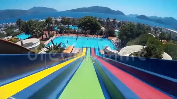 在热带度假胜地的水上乐园里乘坐彩色滑梯的人视频的预览图