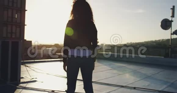 城市屋顶上的时尚年轻女性双臂伸展视频的预览图