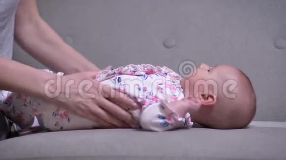 母亲抚摸她可爱的新生女儿躺在客厅沙发上的肖像视频的预览图