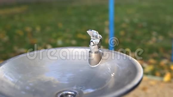 秋季户外儿童游乐场附近的城市公园带有饮用水喷泉的金属水龙头饮用水视频的预览图