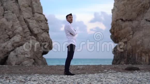 年轻人环顾海边的两座山之间那里的海浪拍打着岩石塞浦路斯帕福斯视频的预览图