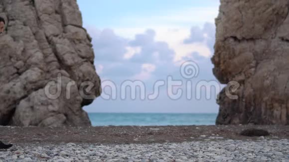 英俊的男人环顾海边的两座山之间那里的海浪拍打着岩石塞浦路斯帕福斯视频的预览图