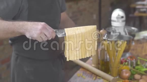 男人在家庭厨房做新鲜的意大利面食厨师把手工制作的生面条放在桌上视频的预览图