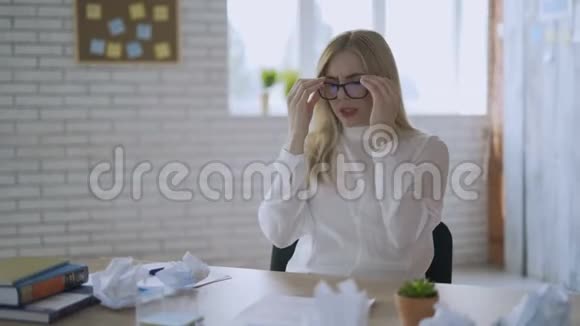 在办公室里用笔记本电脑工作了很长时间后精疲力竭的年轻商务女性摘下眼镜女人的感觉视频的预览图