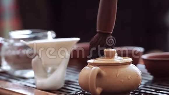 中国的茶道用茶刷把一个小水壶从滚烫的茶滴中擦去视频的预览图