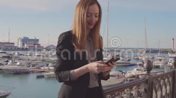 女商人通过移动站在露台上发送信息可以看到港口景观视频的预览图