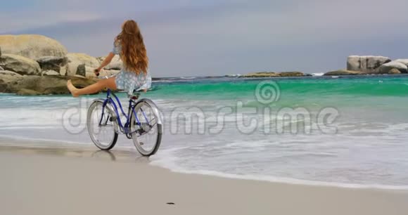高加索女人在海滩上骑自行车的后景视频的预览图