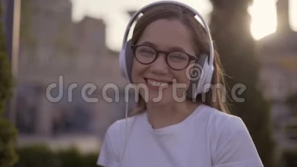 快乐的十几岁女孩在公园里听耳机音乐4K视频的预览图