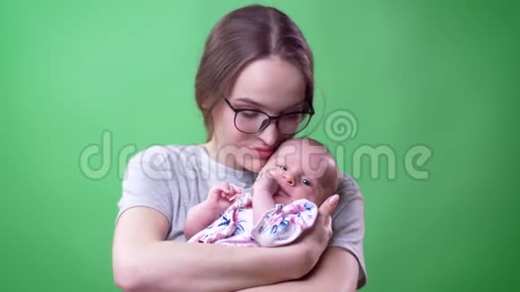 一幅美丽的母亲的特写肖像她摆出一个可爱的新生女儿她在绿色的背景下打着漂亮的哈欠视频的预览图