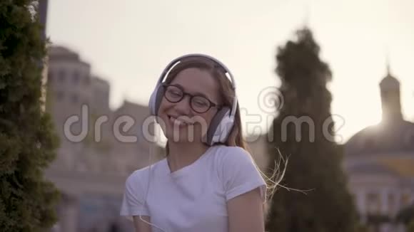 公园里戴着大耳机的嬉皮士女孩女孩看着相机微笑着4K视频的预览图