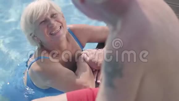 快乐的成熟夫妇一起在酒店综合体的游泳池放松坐在游泳池边上的老人视频的预览图
