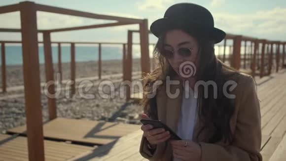 快乐的女孩正坐在城市堤边用智能手机上网视频的预览图