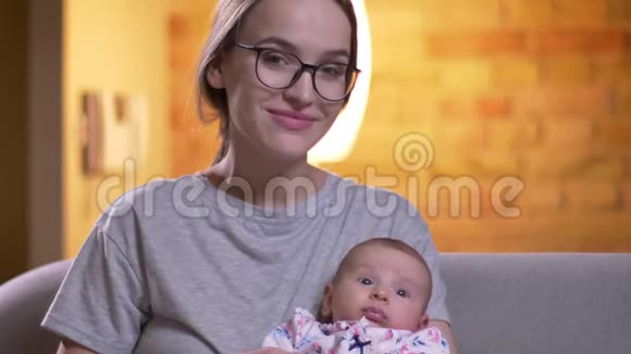 在客厅里妈妈和她可爱的新生女儿抱在一起严肃地看着镜头视频的预览图