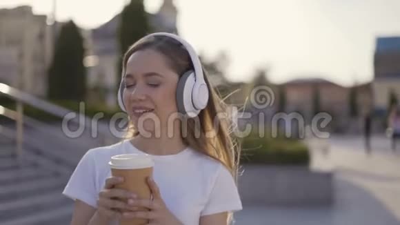 快乐的女孩正在享受街上纸杯里的热饮柔和的光线4K视频的预览图