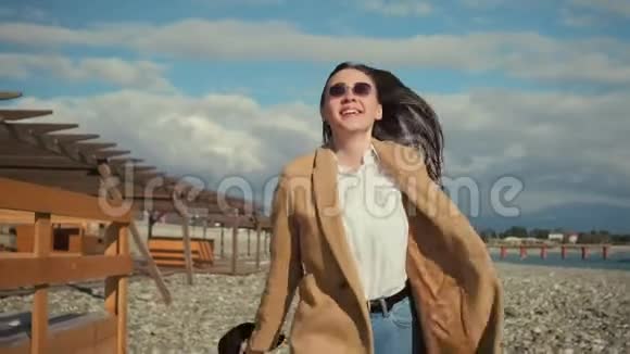 在阳光明媚的天气里时髦的少女在空旷的海滩上跳跃笑容满面视频的预览图