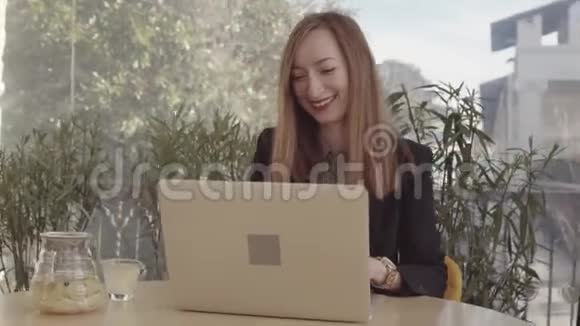 自由职业者妇女坐在咖啡馆里手提电脑一边工作一边喝茶视频的预览图