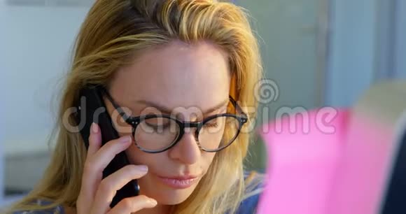 高加索女时装设计师在办公室用手机交谈的正面景色视频的预览图