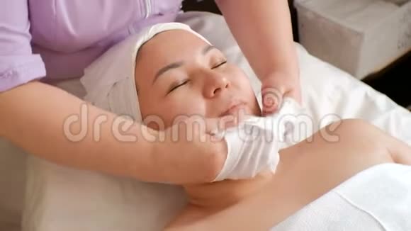 在美容院做手术的亚洲女孩按摩年轻化和面部清洁女人职业女性的手视频的预览图