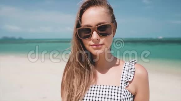 戴着墨镜站在沙滩上直视镜头的女人视频的预览图