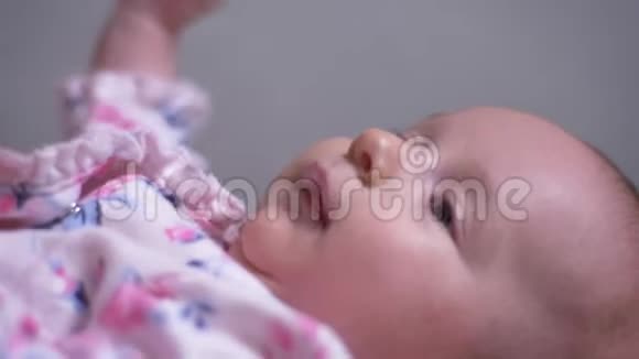 特写肖像可爱美丽的新生女婴躺在沙发上在客厅做鬼脸视频的预览图