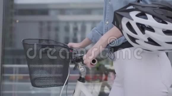 未被认出的年轻苗条迷人的金发女人穿着白色牛仔裤带着她的自行车靠近城市的商店窗户这就是视频的预览图