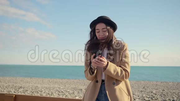 年轻时尚的女孩在海边的智能手机上在社交网络上聊天视频的预览图