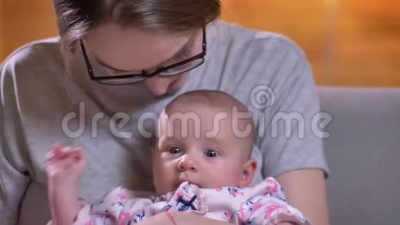 母亲在客厅亲吻她可爱美丽的新生女儿的特写肖像视频的预览图