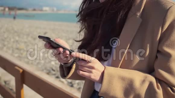 在晴朗的天气里女人手里拿着智能手机站在海上码头视频的预览图