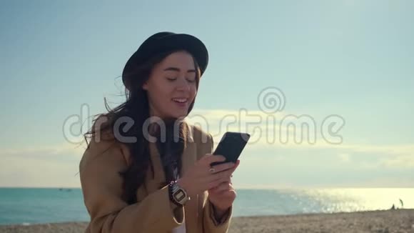少女在手机社交网络上阅读新闻在海滩上微笑视频的预览图