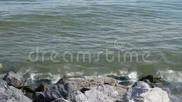 海浪在阳光的照射下翻滚在岩石沙滩上洗涤海岸视频的预览图