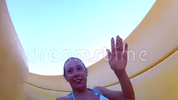 年轻快乐的白人妇女骑着一张开放的滑梯翻滚笑自拍慢动作视频的预览图