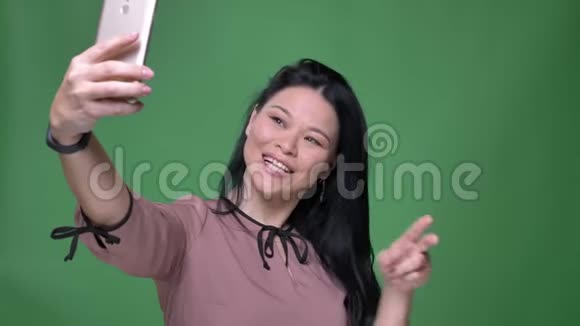 一位年轻迷人的亚洲女性的特写镜头她的黑发在电话上自拍在前面摆姿势视频的预览图