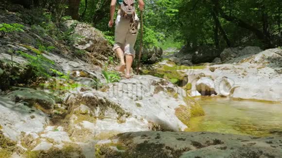 一个孤独的赤脚红发女孩沿着一条干净的山河沿着峡谷的底部行走视频的预览图
