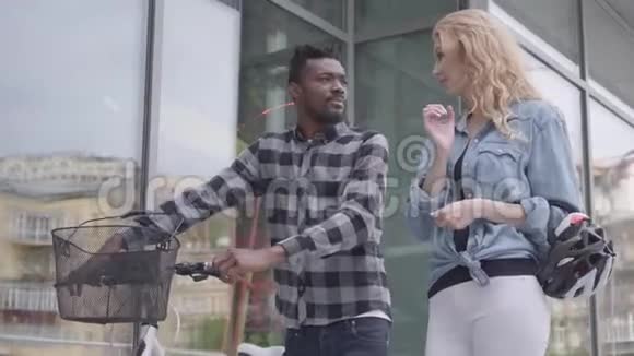 肖像英俊自信的非裔美国人穿着休闲服装骑着自行车靠近城市的商店橱窗视频的预览图