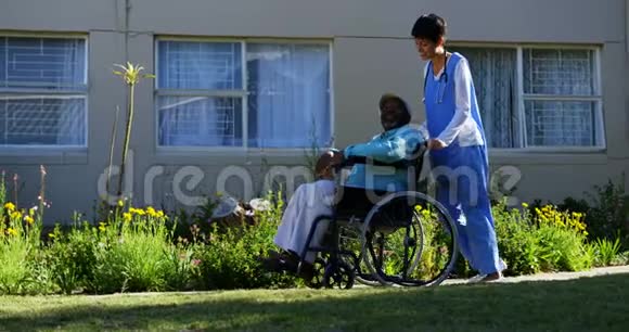高加索女医生将轮椅上的老年患者推至养老院侧视4k视频的预览图