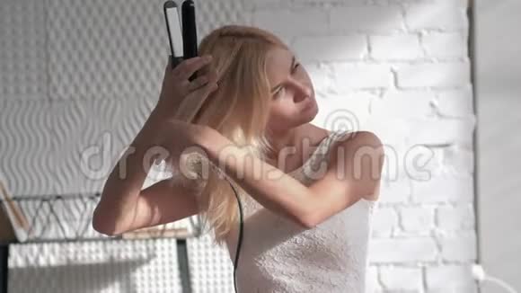头发护理微笑的年轻金发女人做发型房间里有矫直机视频的预览图