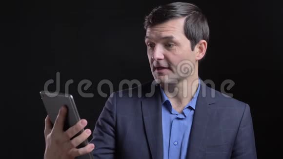 穿着紧身衣拍摄的成年白种人他在平板电脑上打了一个视频电话背景是黑色的视频的预览图