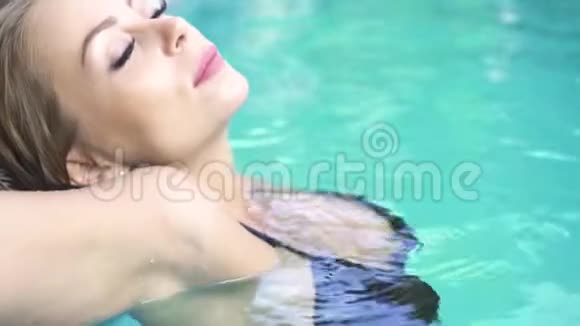 美丽的女人在炎热的晴天在游泳池里享受淡水穿着黑色比基尼放松的美女视频的预览图