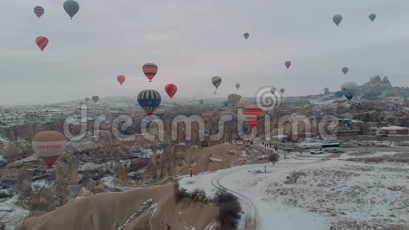 在卡帕多西亚五颜六色的热空气气球飞过仙女的烟囱和雪视频的预览图