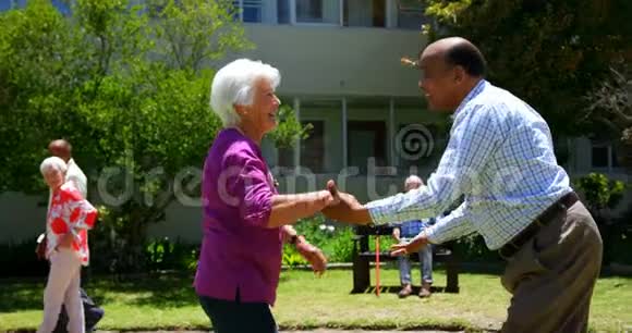 在养老院的花园里活跃的混血儿夫妇一起跳舞的侧景视频的预览图