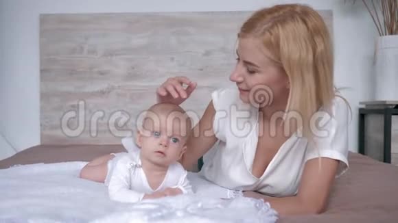 母亲带着女儿为躺在床上的相机摆姿势父母轻轻地亲吻和拥抱她的新生女孩视频的预览图