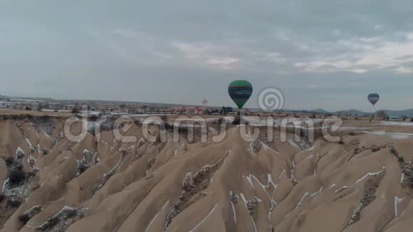 在卡帕多西亚日出时白雪皑皑的仙女烟囱上飘着五颜六色的热气球视频的预览图