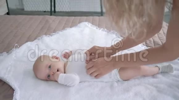 母亲和刚出生的女孩玩得很开心她躺在白色的床上紧紧地咬着手指视频的预览图