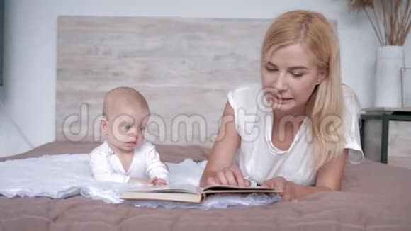 爱的妈妈带着书给躺在家里的宝贝女儿讲童话故事视频的预览图