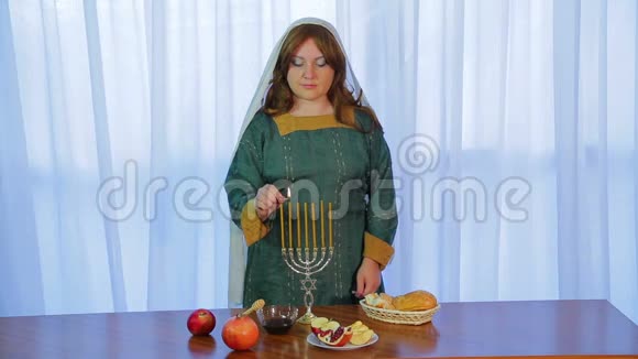 在节日聚会上一位犹太妇女在一个美丽的烛台上用糖果点燃蜡烛视频的预览图