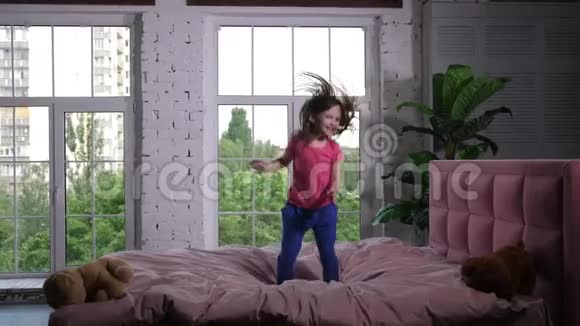 快乐的小孩在卧室的舒适的床上蹦蹦跳跳视频的预览图