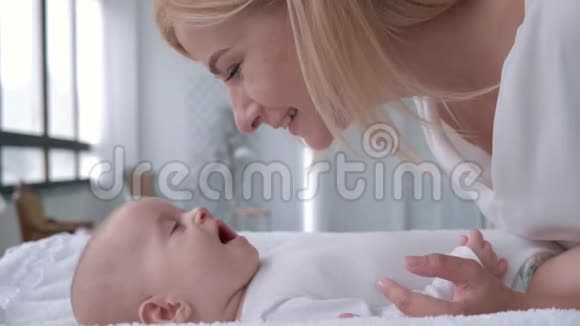 产妇微笑的母亲说话和温柔的玩耍她的小女孩躺在换桌子上近距离视频的预览图