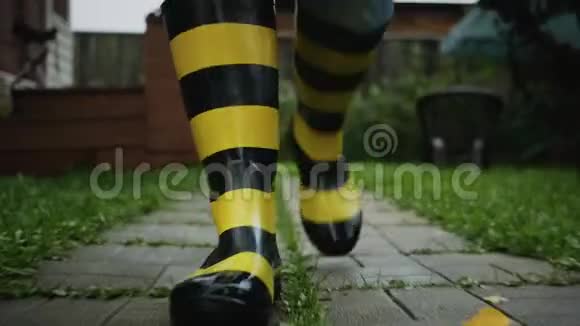 一个男人穿着黑色和黄色的条纹橡胶靴子沿着跑道走视频的预览图